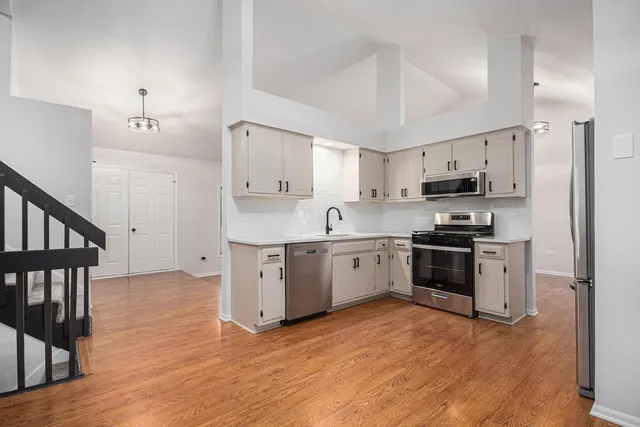 a kitchen with granite countertop a refrigerator stove a sink and dishwasher with wooden floor