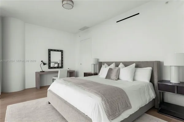 a bedroom with a white bed and wooden floor