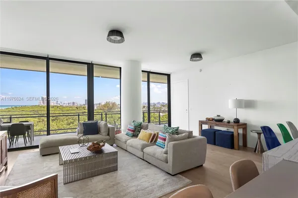 a living room with furniture and floor to ceiling window next to a yard