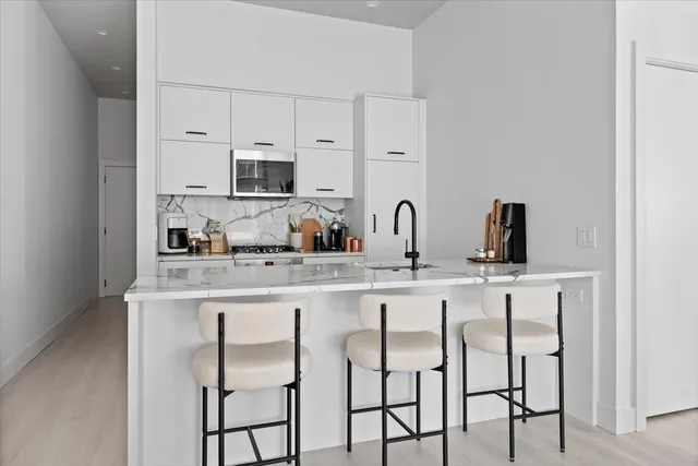 a kitchen with cabinets a sink and chairs in it