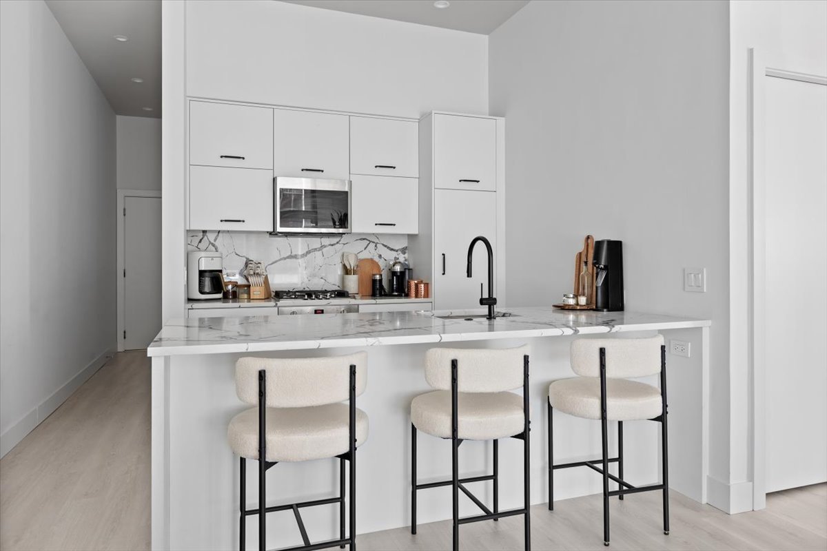 949 West Madison Street, Unit 406 Chicago, IL 60607 - Photo 5 of 16 a kitchen with cabinets a sink and chairs in it