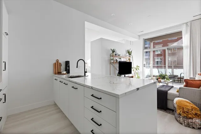 a large white kitchen with a sink and dishwasher a stove with wooden floor