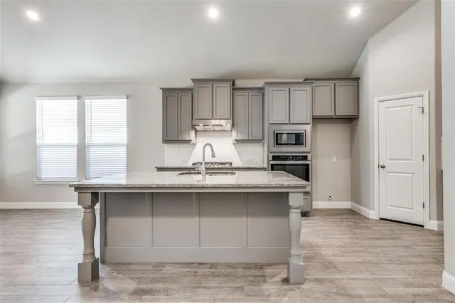 a kitchen with stainless steel appliances granite countertop a sink window and cabinets