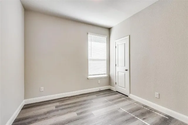 an empty room with wooden floor and window