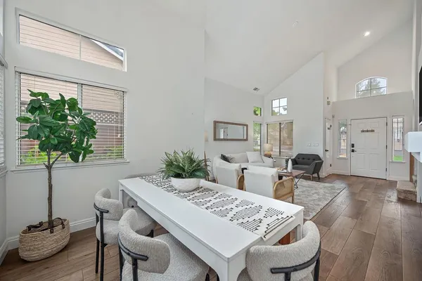 a kitchen with stainless steel appliances granite countertop a stove a sink a refrigerator and white cabinets with wooden floor