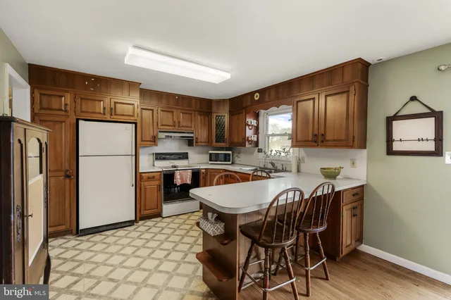 a kitchen with stainless steel appliances granite countertop a dining table chairs refrigerator and cabinets