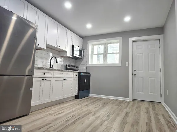 a kitchen with white cabinets and refrigerator