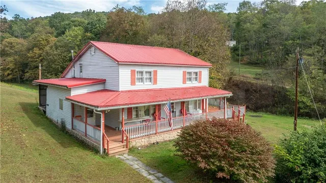 a view of a house with a yard balcony and trees in the background