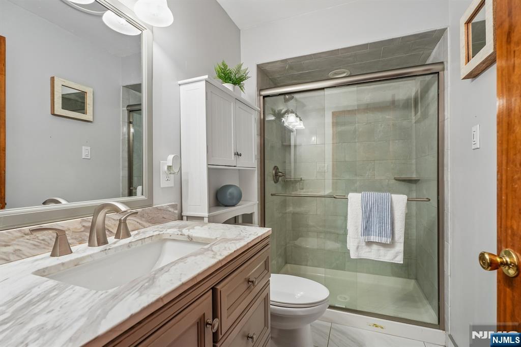 40 Golf Road Bloomfield, NJ 07003 - Photo 38 of 50 a bathroom with a granite countertop sink a toilet a mirror and shower
