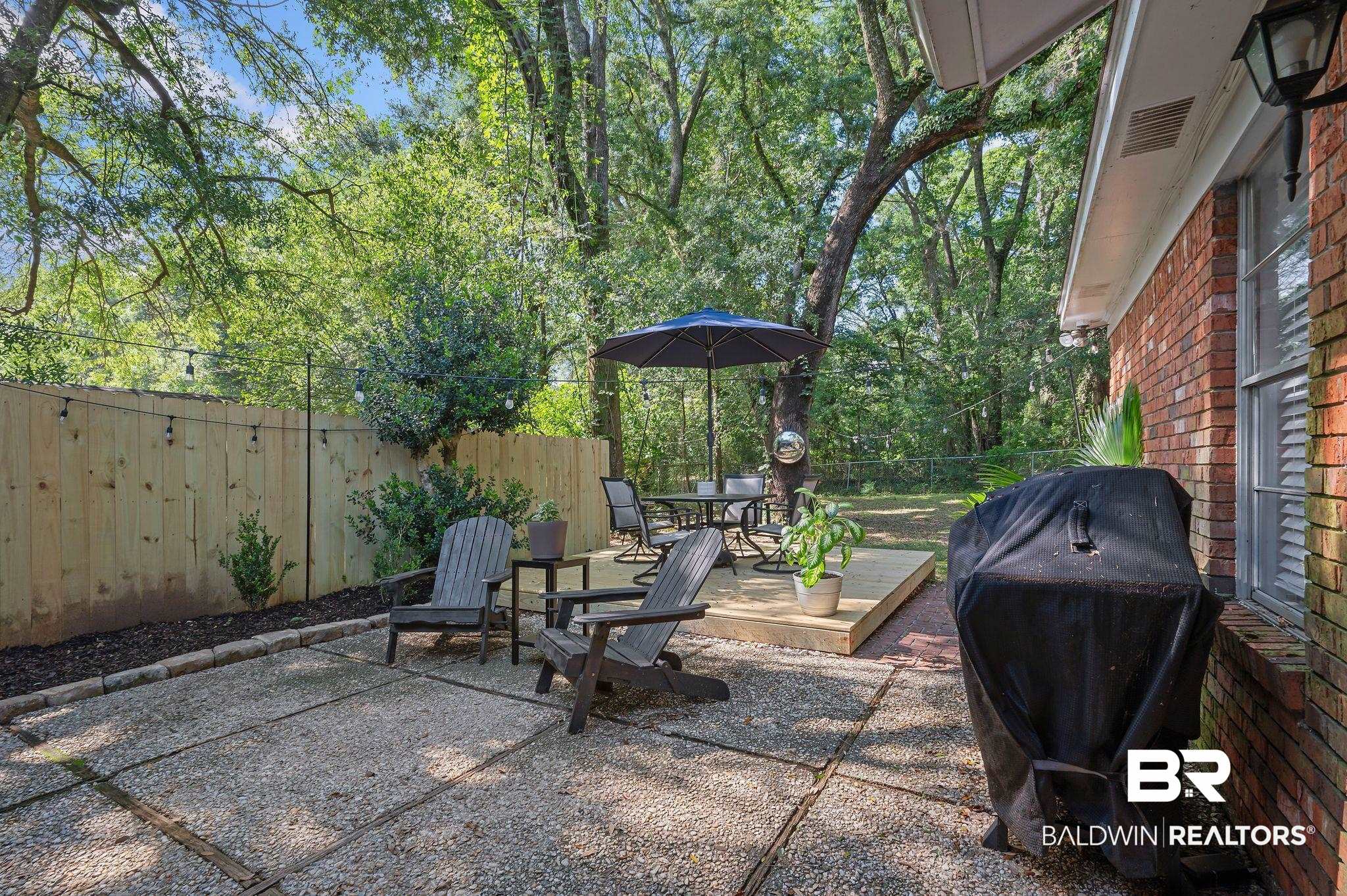 4724 Wicker Way Mobile, AL 36609 - Photo 31 of 36 Expansive outdoor space featuring a textured concrete patio, a newly installed wooden privacy fence, and mature trees providing natural shade
