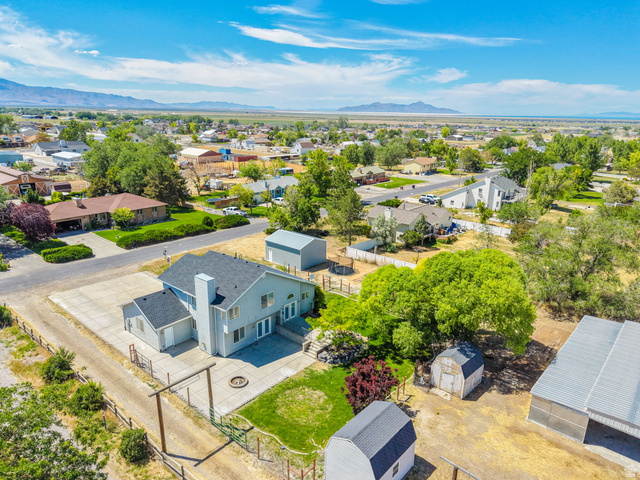 3732 Campbell Road Tooele, UT 84074 - Photo 47 of 69 Expansive property featuring a light blue exterior, a detached storage shed, a separate barn structure, a fenced yard area, and a concrete patio with a fire pit
