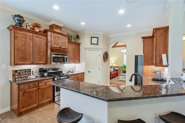a kitchen with stainless steel appliances granite countertop a sink stove and cabinets