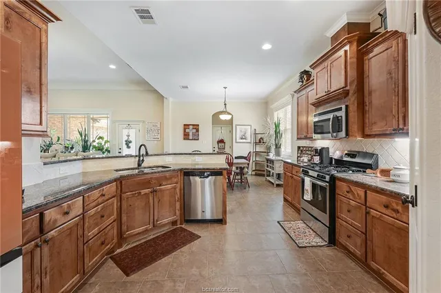 a kitchen with stainless steel appliances granite countertop sink stove top oven and cabinets