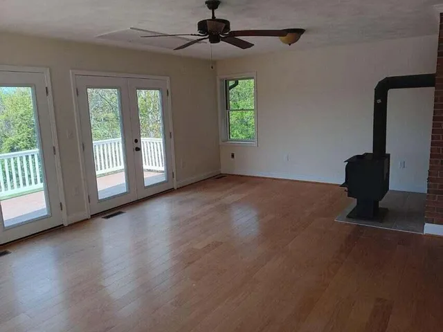 a view of an empty room with a window and wooden floor