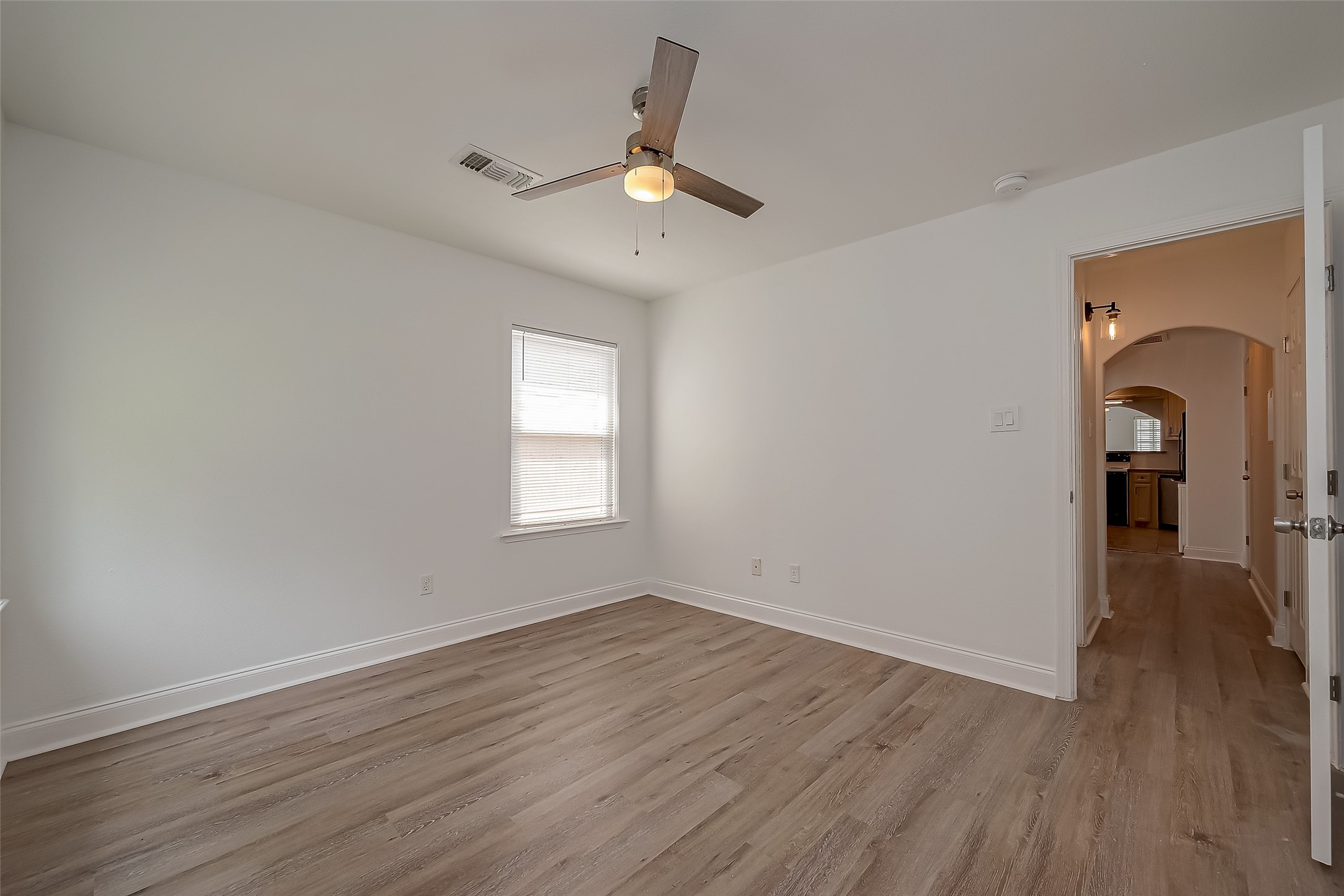 917 Adele Street Houston, TX 77009 - Photo 12 of 24 Spacious primary bedroom with warm laminate floors, ceiling fan, and natural light.
