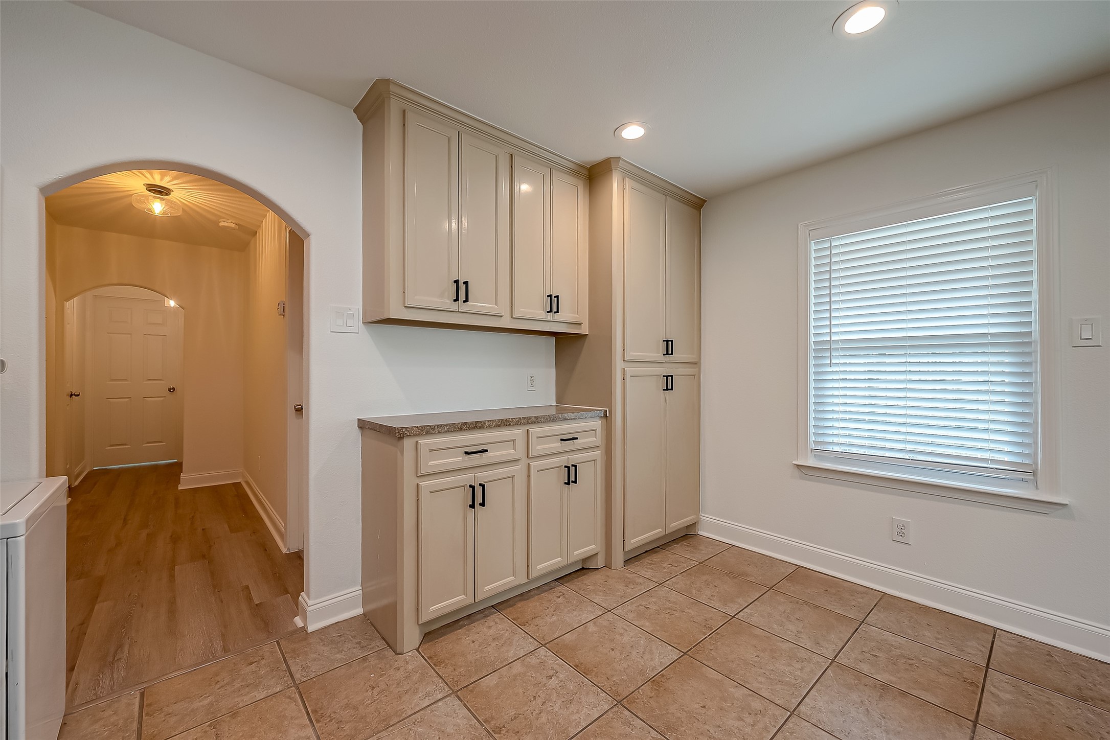 917 Adele Street Houston, TX 77009 - Photo 7 of 24 Cream cabinetry with black hardware, tile floors, and a beautiful arched doorway. Plenty of storage throughout.