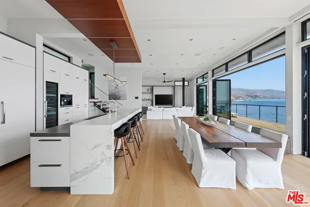 a large living room with stainless steel appliances kitchen island granite countertop furniture a fireplace and a large window