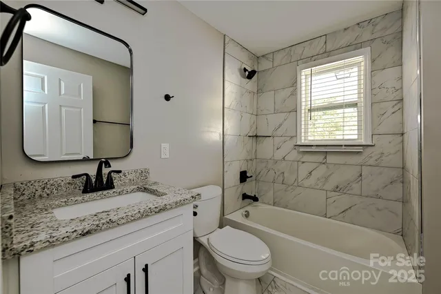 a bathroom with a granite countertop toilet a sink and bathtub