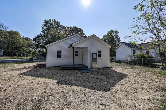 a view of a white house next to a yard with a large tree