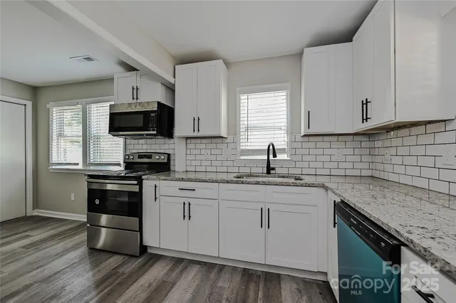 a kitchen with stainless steel appliances granite countertop a sink a stove a microwave a sink and cabinets