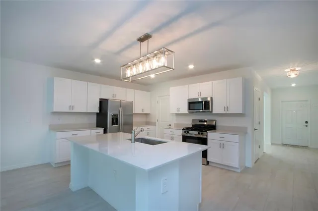 a kitchen with kitchen island white cabinets and refrigerator