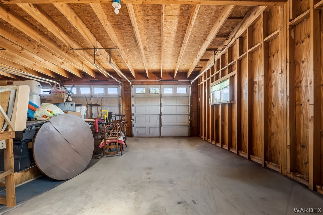 2401 North Stephan Road Kingman, AZ 86401 - Photo 70 of 92 Spacious garage featuring a concrete floor, exposed wood framing, two garage doors with upper window panels, a side window, and overhead lighting