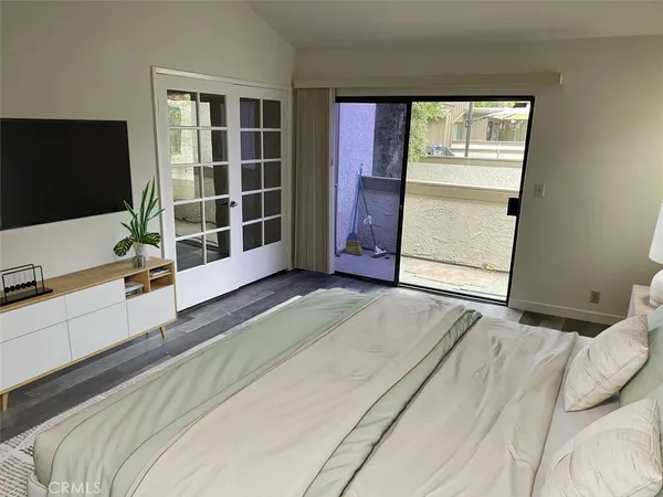 a spacious bedroom with a bed and a flat screen tv