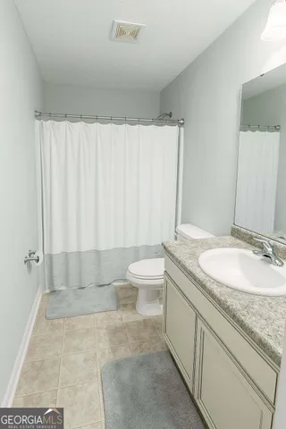 a bathroom with a granite countertop sink a toilet and a mirror