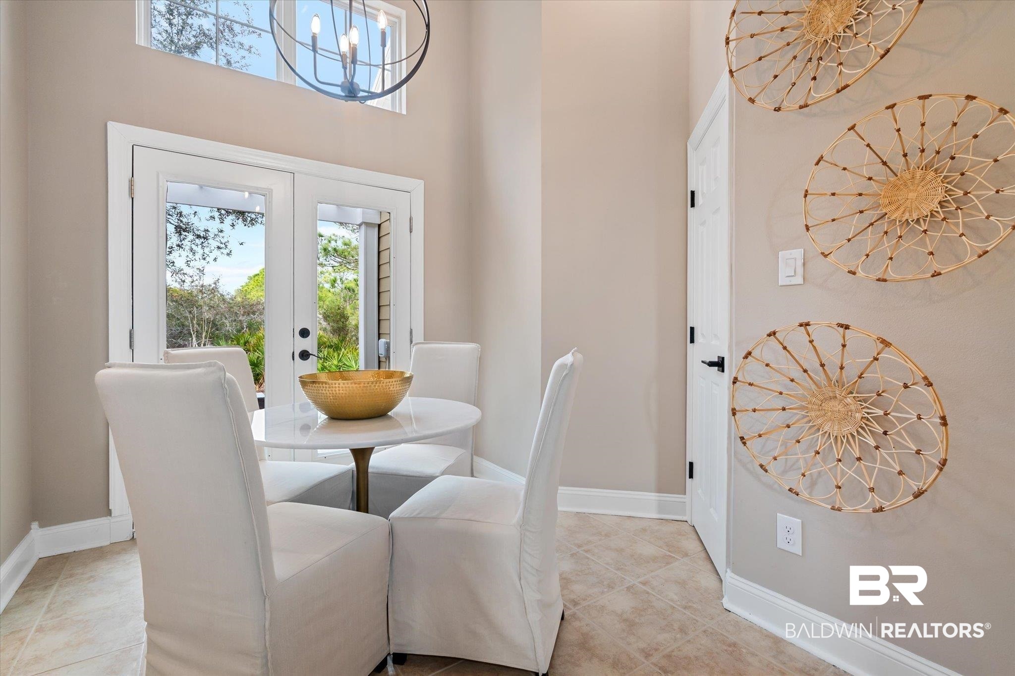 9259 Genipa Way Gulf Shores, AL 36542 - Photo 11 of 72 Tiled dining room featuring a towering ceiling, a notable chandelier, and french doors