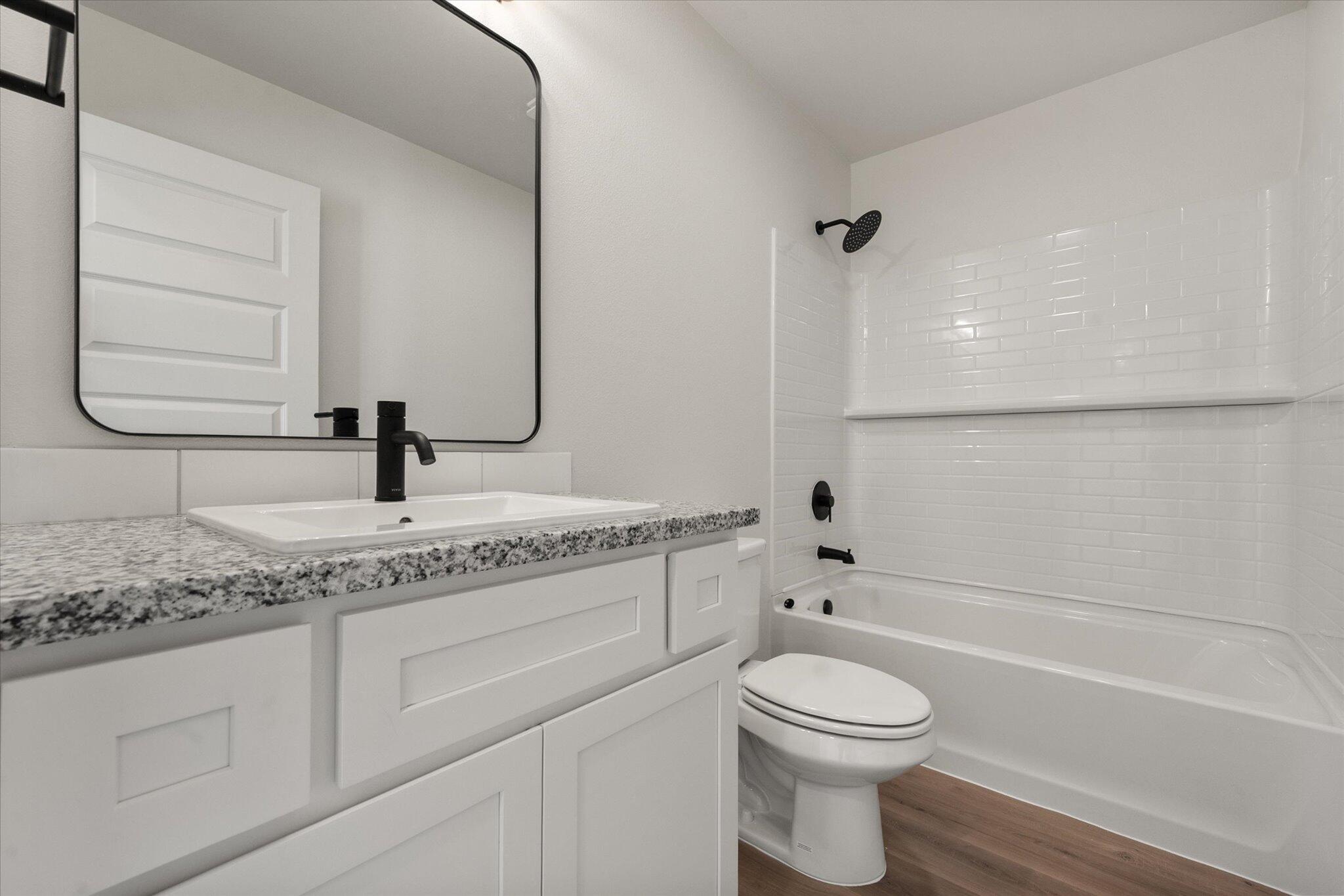 6308 Volney Avenue Lubbock, TX 79407 - Photo 14 of 19 a bathroom with a granite countertop toilet a sink and a bathtub