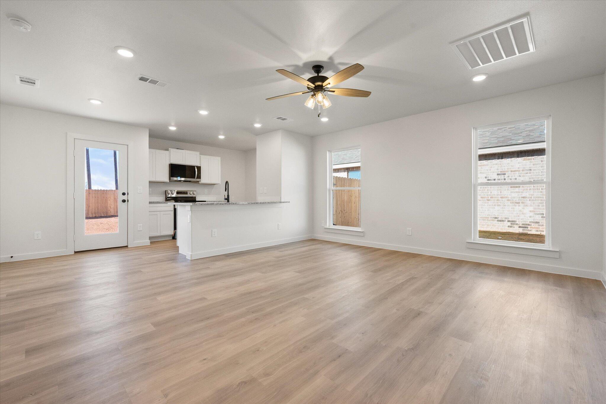 6308 Volney Avenue Lubbock, TX 79407 - Photo 3 of 19 a view of a kitchen with a stove cabinets a ceiling fan and wooden floor