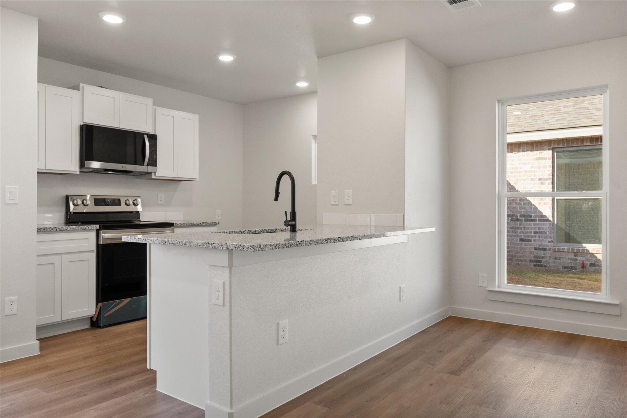 6308 Volney Avenue Lubbock, TX 79407 - Photo 7 of 19 a kitchen with stainless steel appliances granite countertop a sink a microwave a refrigerator and grey cabinets