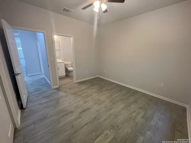 a view of a room with wooden floor and a ceiling fan