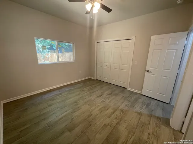 an empty room with wooden floor fan and windows