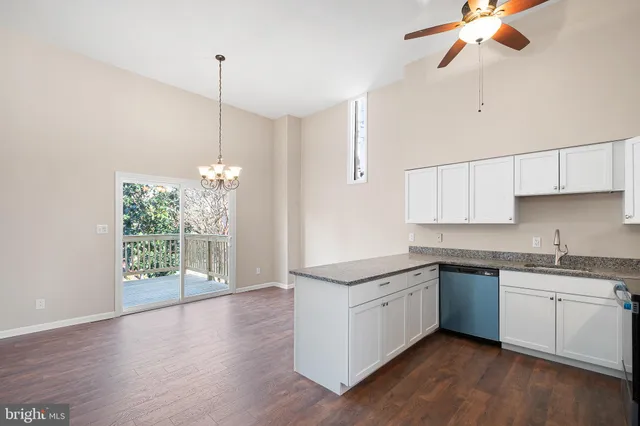 a kitchen with stainless steel appliances granite countertop a sink a window and white cabinets
