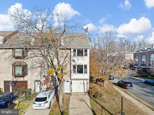 a view of a brick house with large trees and wooden fence