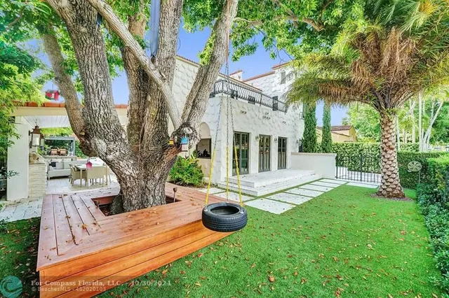 a palm tree sitting in front of a house with a yard