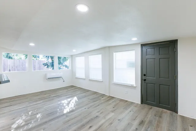 an empty room with wooden floor cabinet and windows