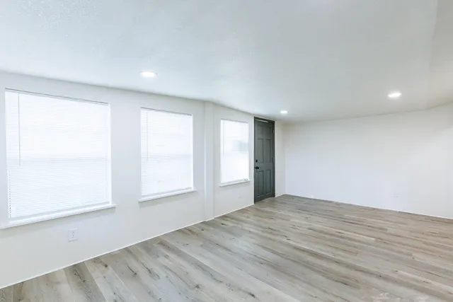 an empty room with wooden floor and windows