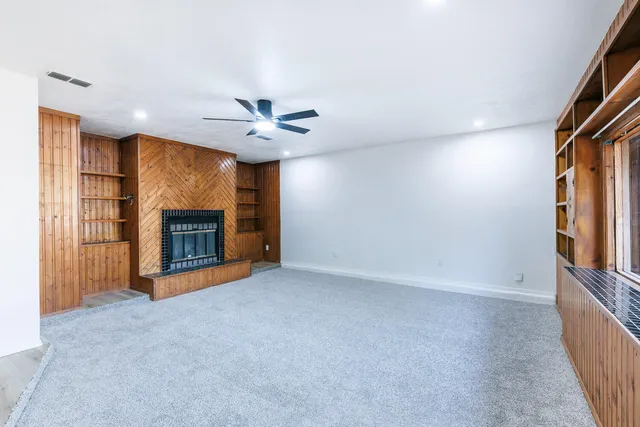 an empty room with windows and fireplace