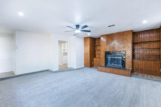 an empty room with windows and ceiling fan