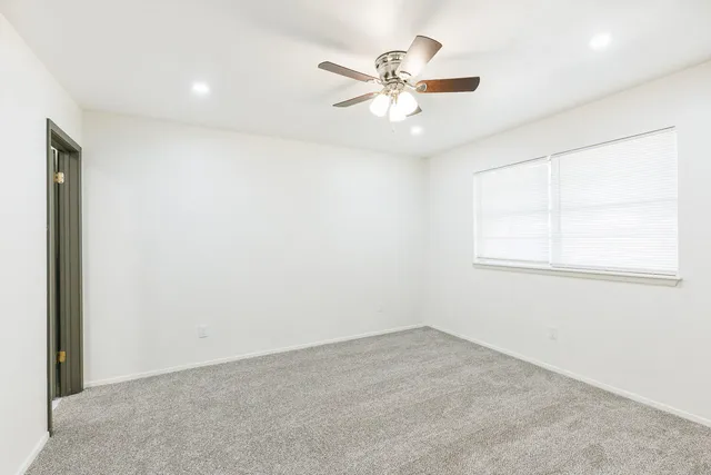 an empty room with a window and a fan