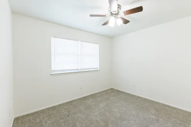 an empty room with a window and a fan