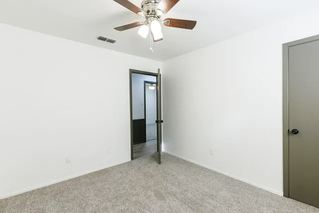 an empty room with closet and a chandelier fan
