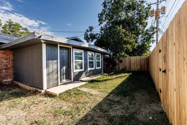 a view of backyard of house with wooden fence and large trees