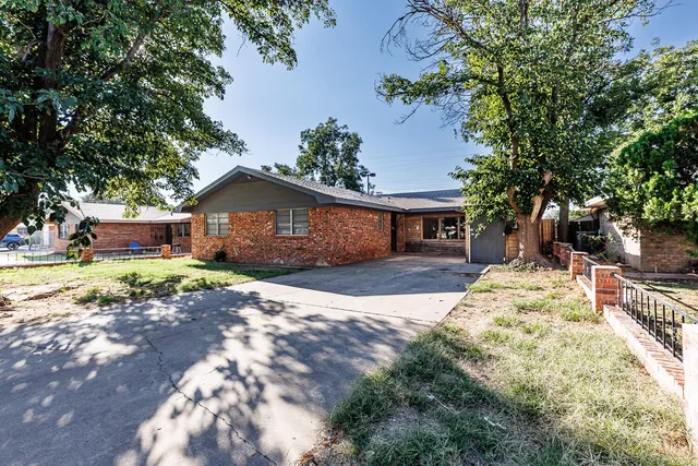 a front view of a house with a garden and tree