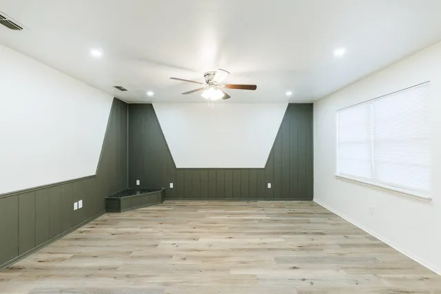 an empty room with wooden floor and fan