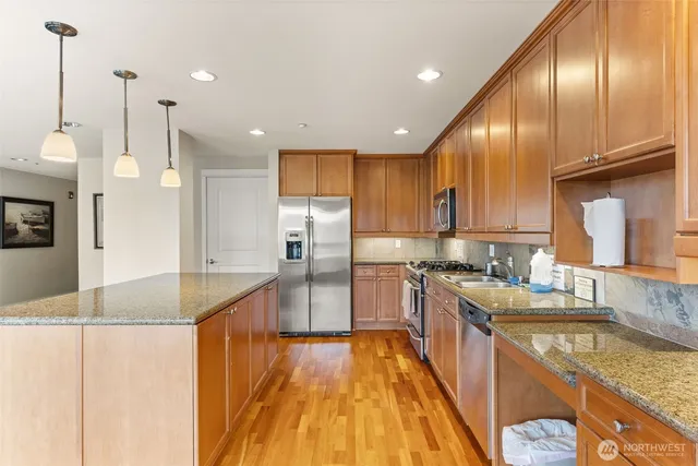 a large kitchen with stainless steel appliances granite countertop a sink a stove and a refrigerator
