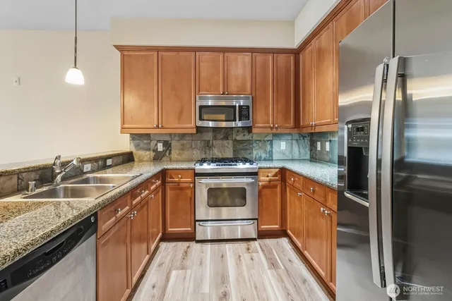 a kitchen with granite countertop a sink stove and refrigerator