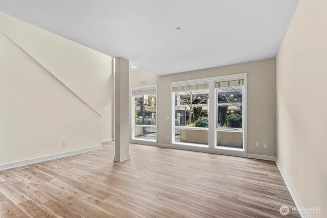 a view of an empty room with wooden floor and a window